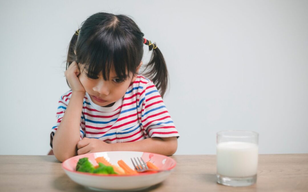 a girl stares at a plate of veggies