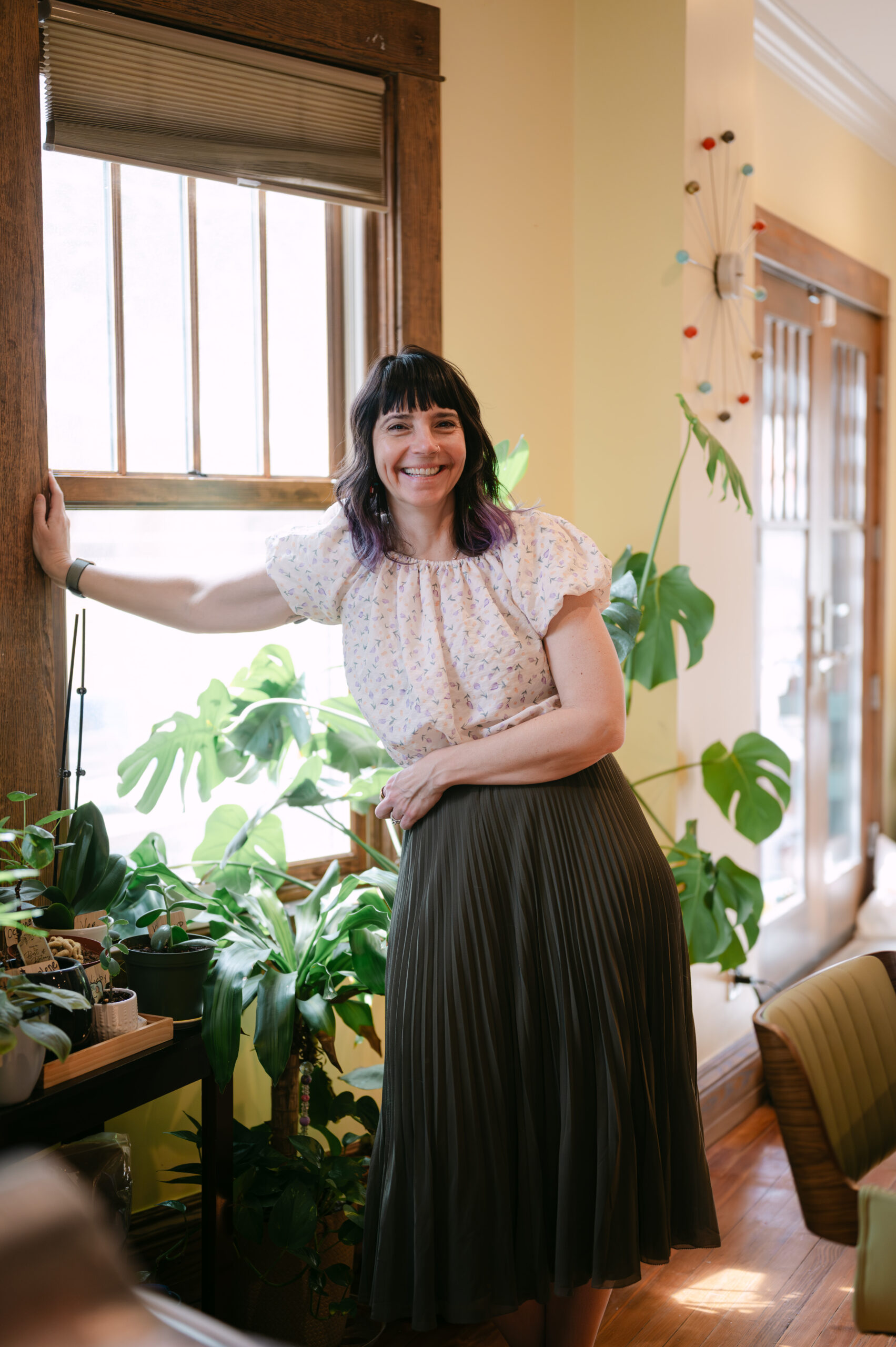 Tiffany Nieslanik stands in a sunny room with plants behind her.