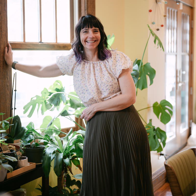 Tiffany Nieslanik stands in a sunny room with plants behind her.